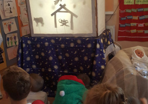Dzieci obserwują teatrzyk cieni.